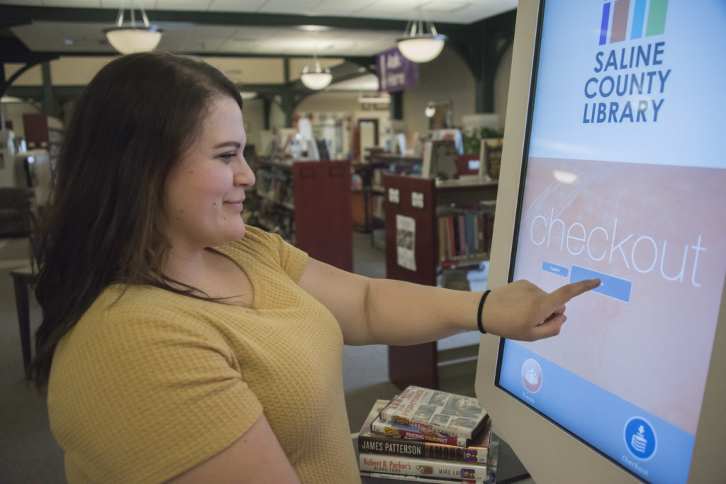Woman using the touch screen kiosk to reserve a book